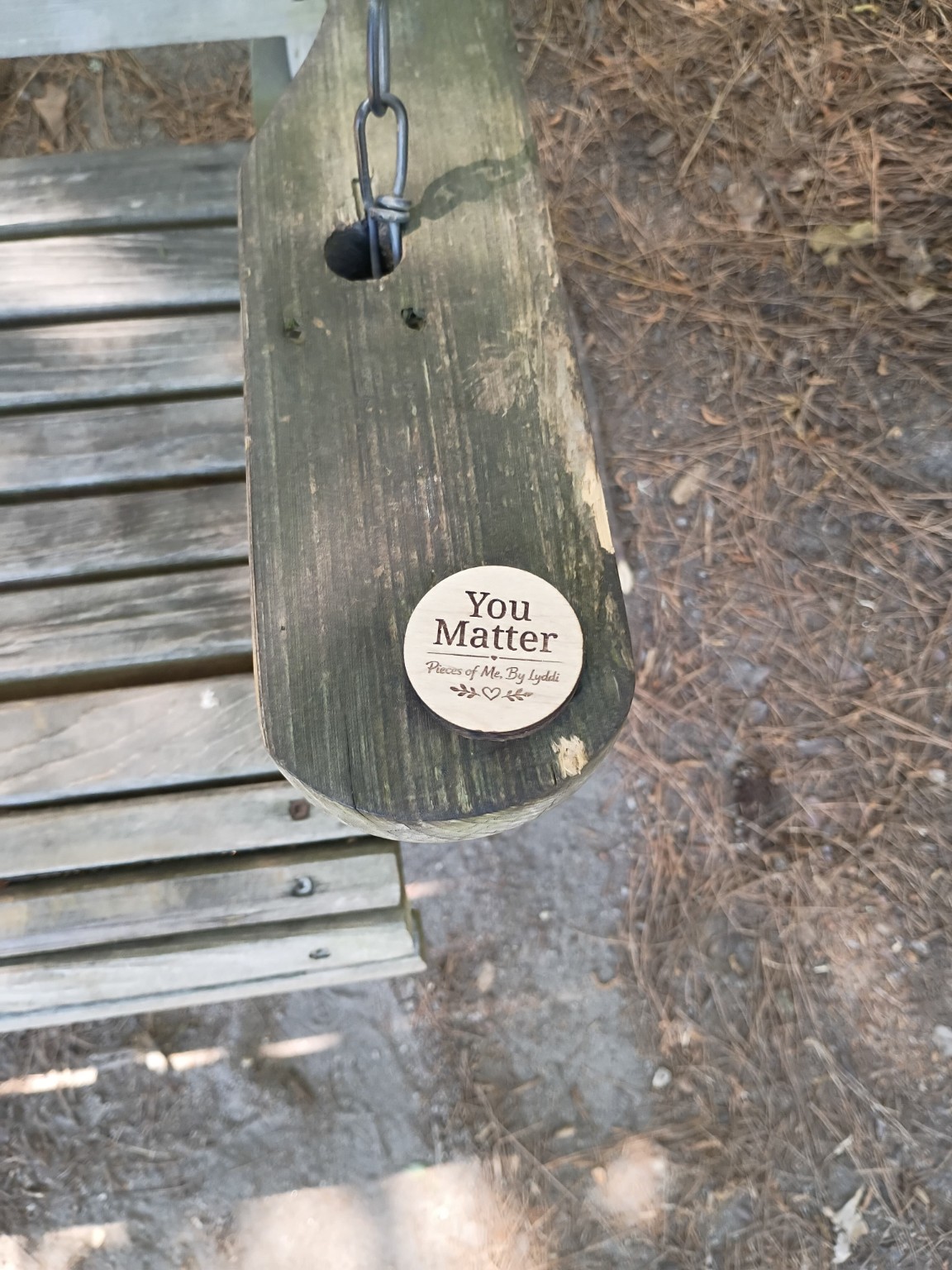 A heartwork token resting on an outdoor public bench