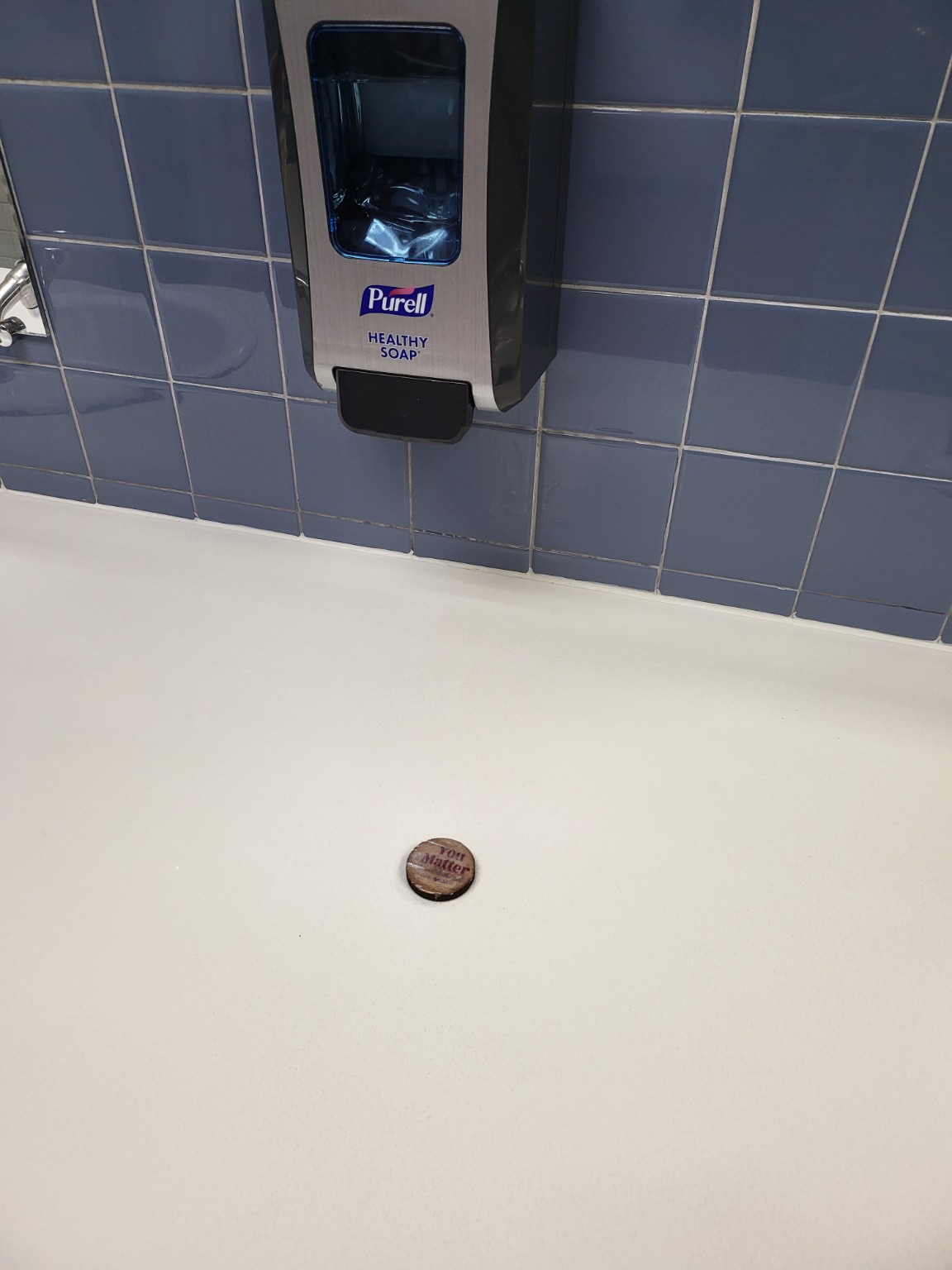 A heartwork token placed in a public sink area beneath a soap dispenser