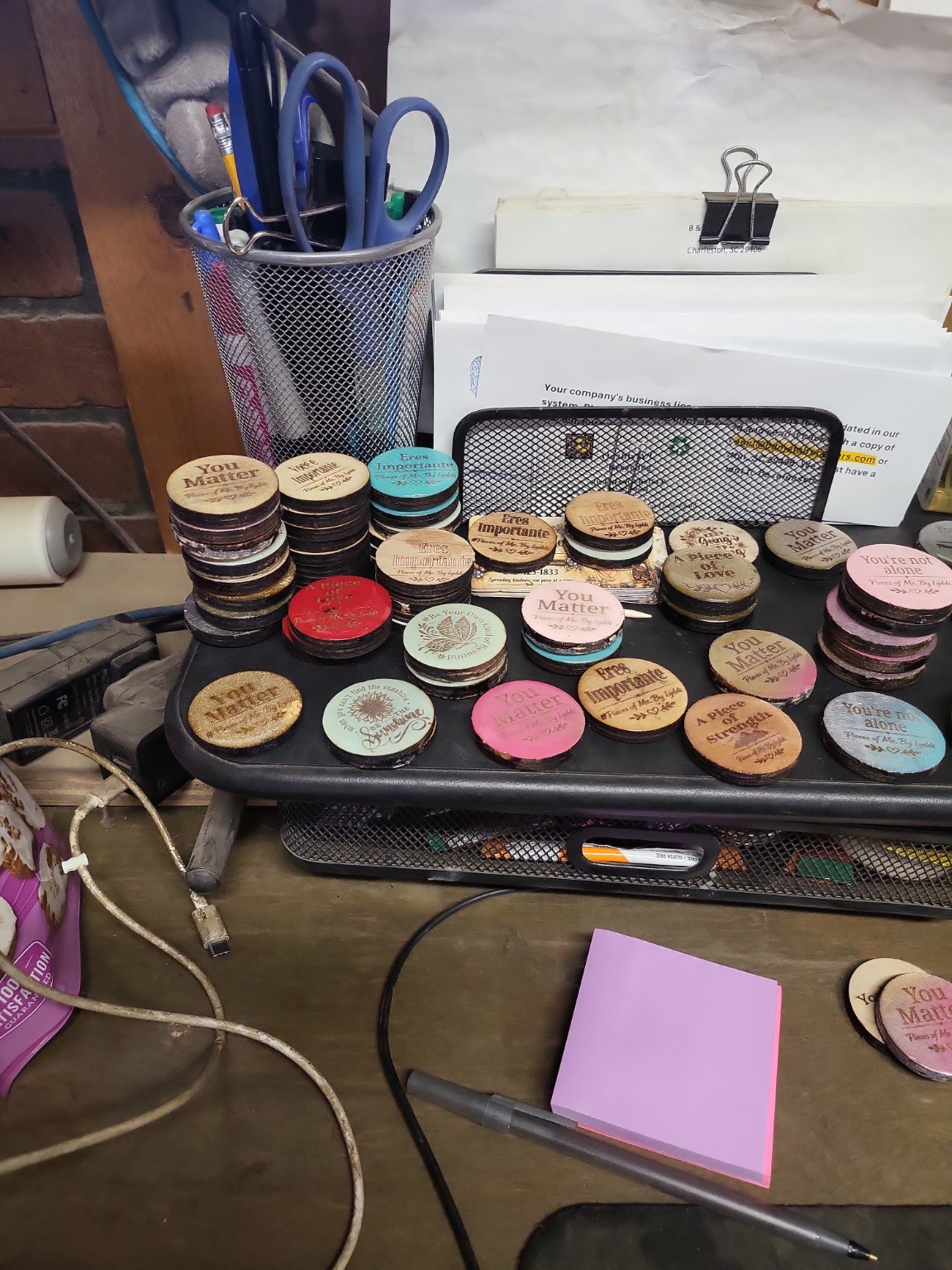 Many handmade tokens arranged beside Lyddi's tools and work area