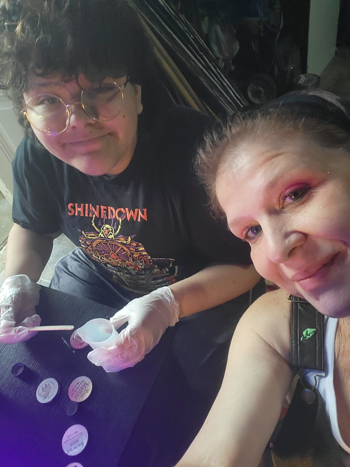 Zanita carefully adding resin to a handmade token while helping Lyddi with the heartwork