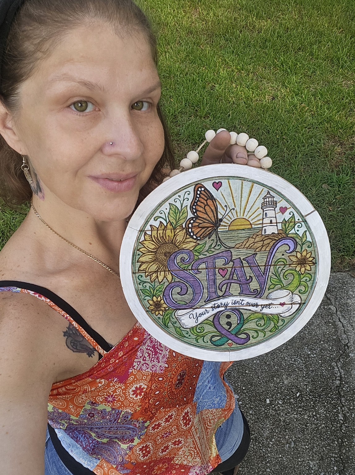 Lyddi holding a fully colored seven-inch round STAY artwork for scale