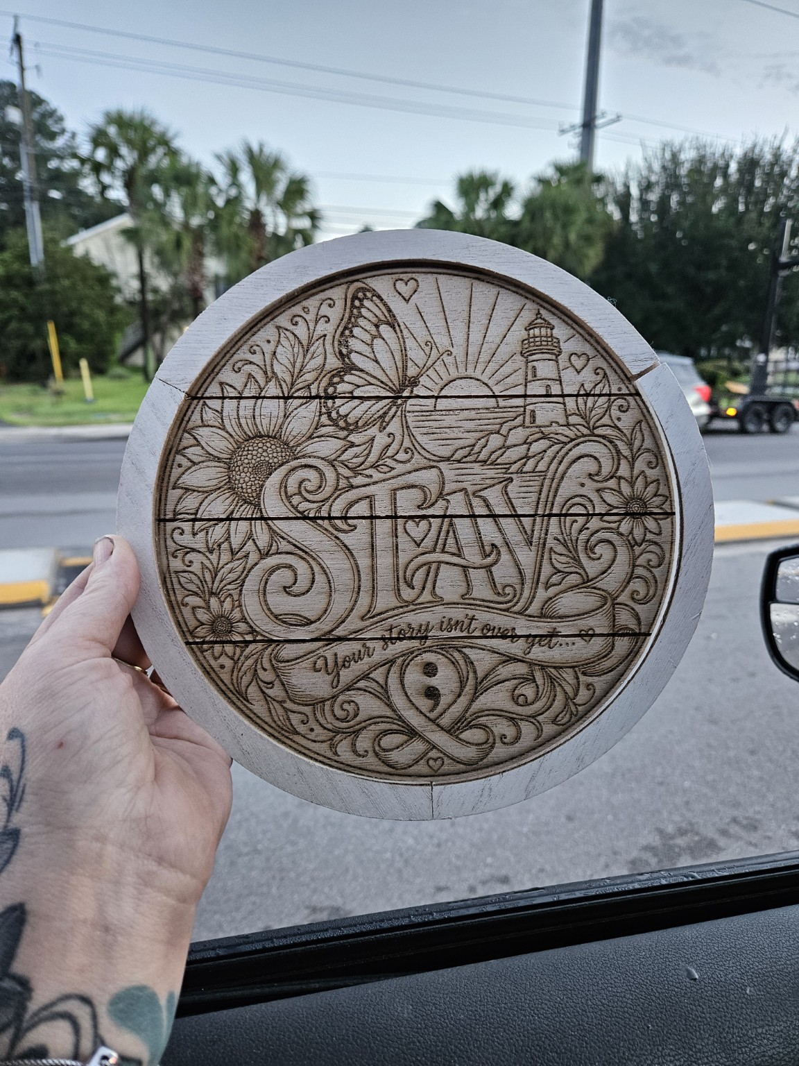 Natural unpainted seven-inch round STAY wooden artwork held in hand for scale