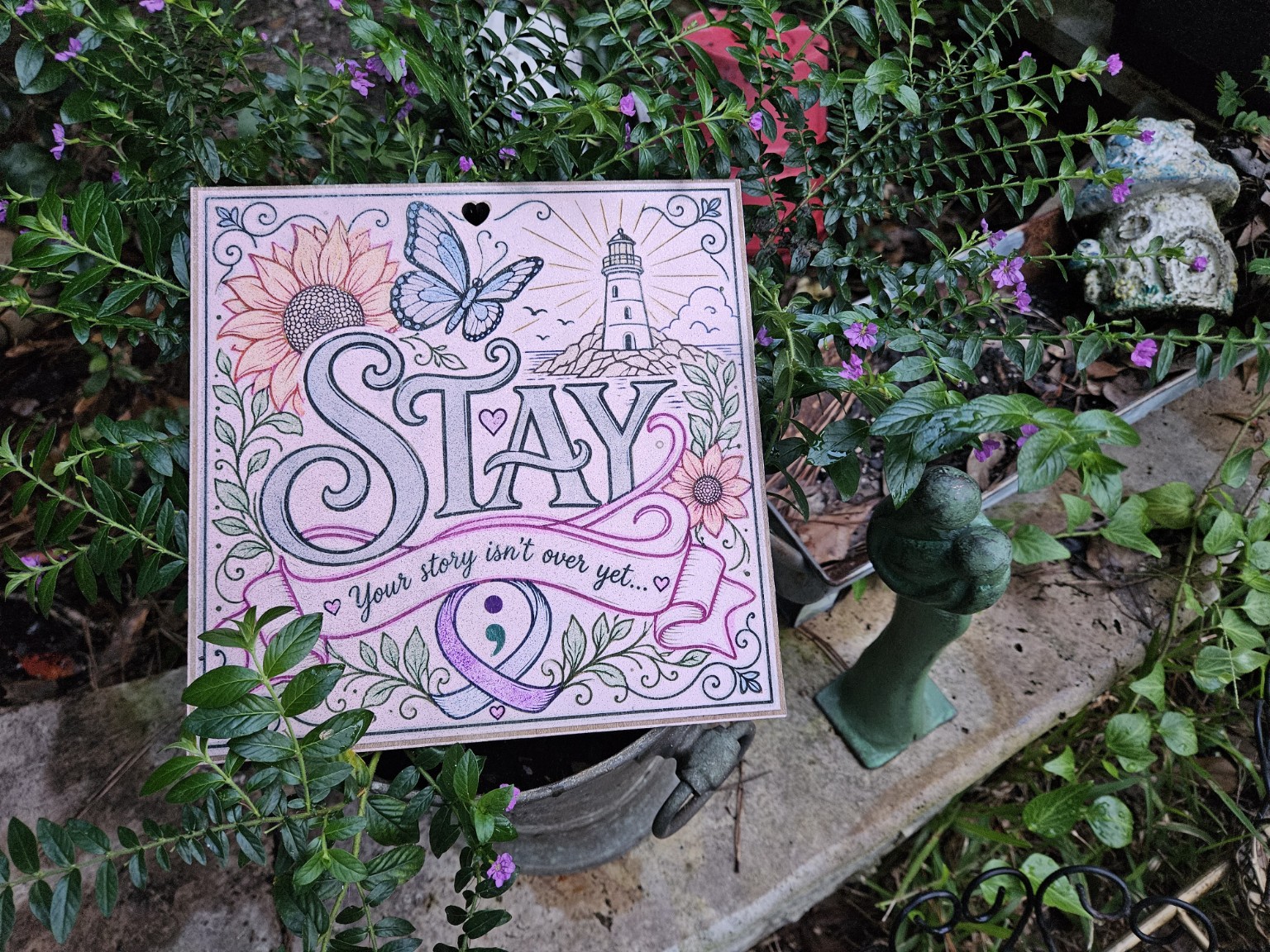 Painted seven-inch square STAY wooden artwork in a garden setting